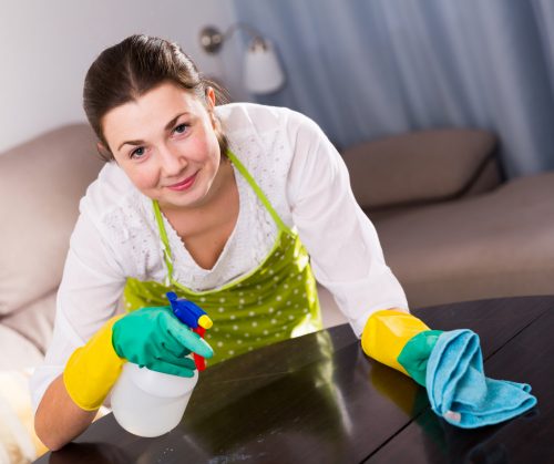 Young girl carefully clean the table with detergent